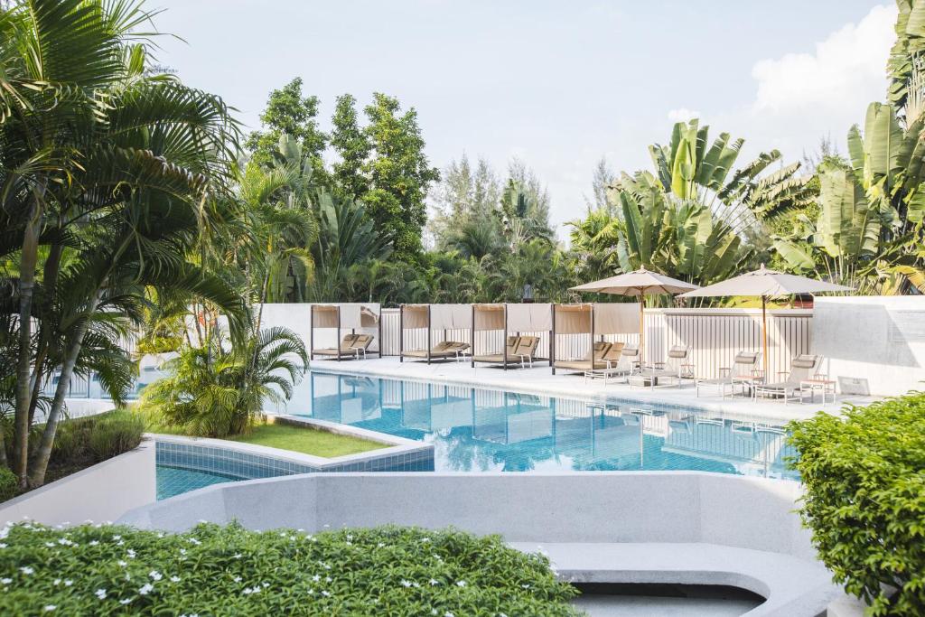 a swimming pool with lounge chairs and umbrellas at Dewa Phuket Resort & Villas in Nai Yang Beach