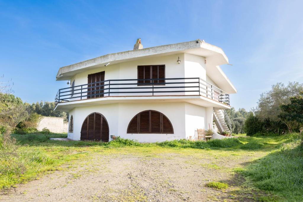 una vecchia casa bianca con balcone su una strada sterrata. di Domu de Campu a Pabillonis