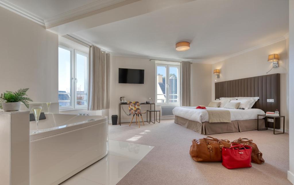 een grote hotelkamer met een bed en een wastafel bij Hôtel L'Orée des plages in Clohars-Carnoët