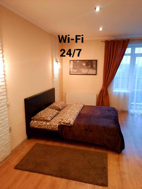 a bedroom with a bed with a sign on the wall at Квартири подобово Івано-Франківська Nice apartments for booking in Ivano-Frankivsʼk
