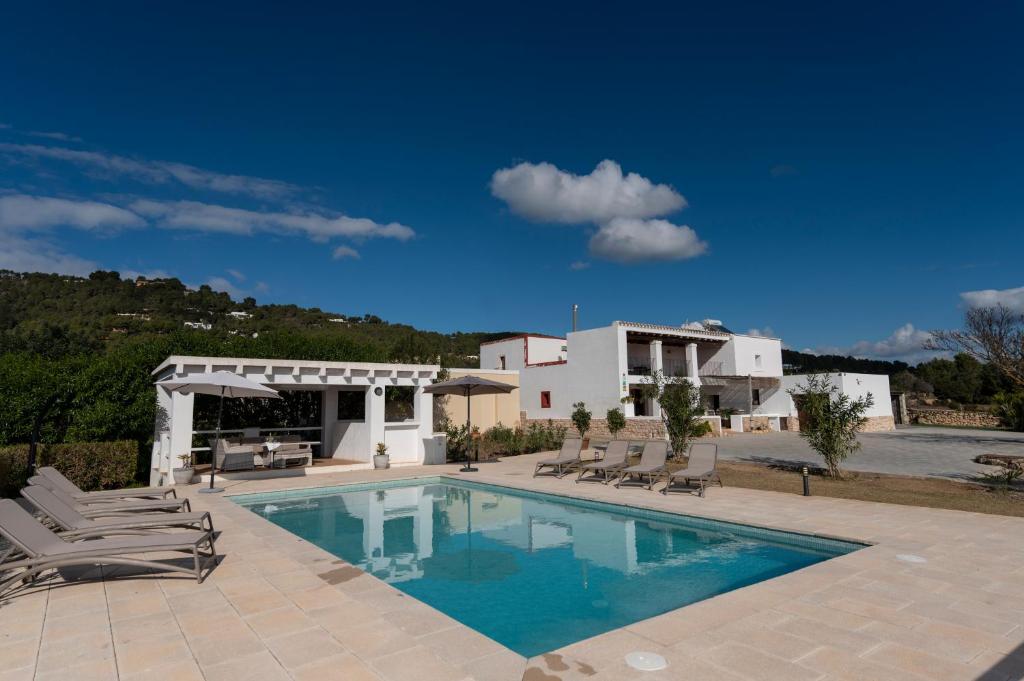a swimming pool with chairs and a house at VILLA ES CUBELLS COUNTRY & SEA in Es Cubells