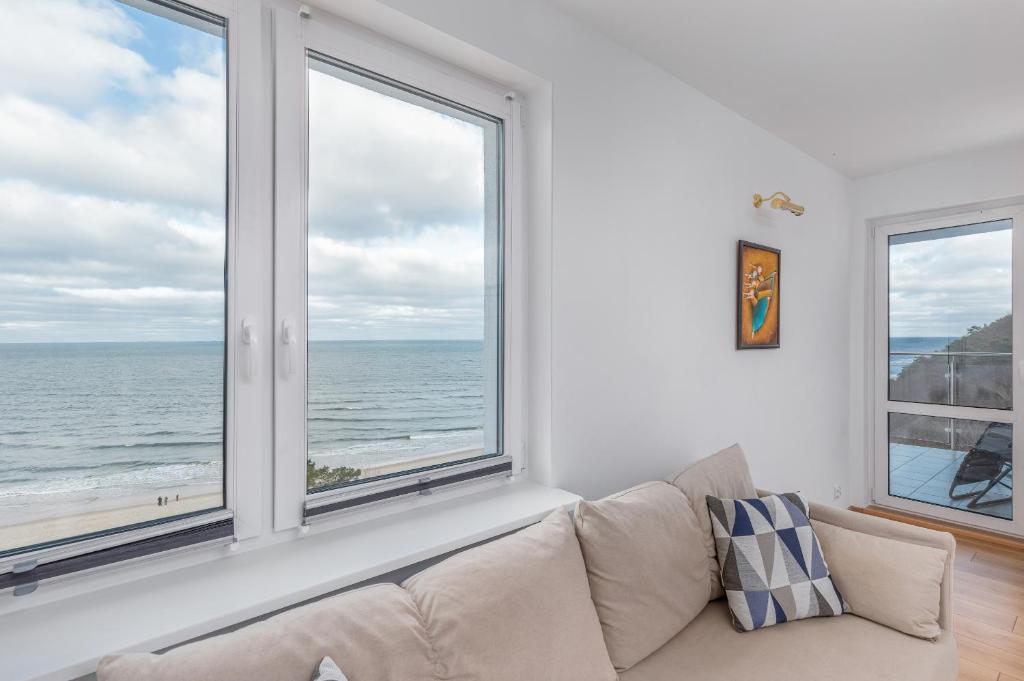 salon z kanapą i dwoma dużymi oknami w obiekcie Apartament przy Plaży - Campingowa - Widok na Morze by Noclegi Renters w mieście Międzyzdroje