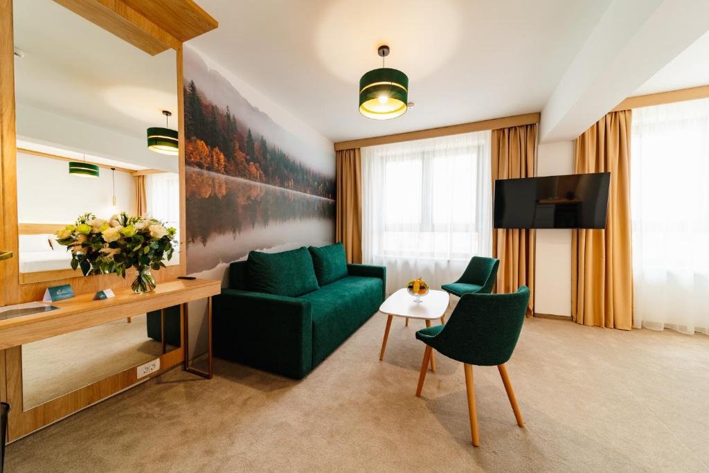 - un salon avec un canapé vert et une télévision dans l'établissement Hotel Küküllő - Târnava, à Odorheiu Secuiesc