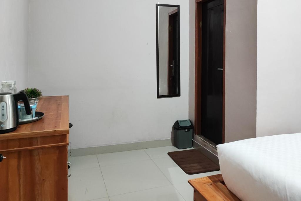 ein Hotelzimmer mit einem Bett und einem Tisch sowie einem Zimmer in der Unterkunft RedDoorz Syariah Near Tugu Macan Kayu Aro in Kayu Aro