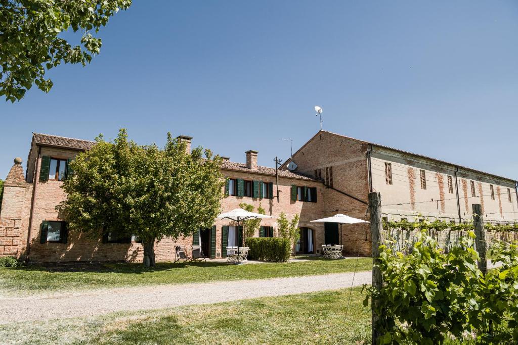 un viejo edificio de ladrillo con un árbol delante de él en Agriturismo Dominio di Bagnoli en Bagnoli di Sopra