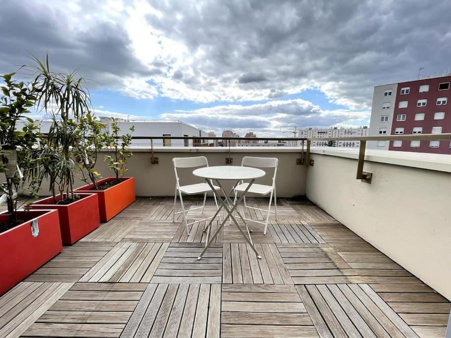 a patio with a table and chairs on a balcony at Superbe Appartement en Résidence T3,Options Clim et parking, lave-linge in Bagneux