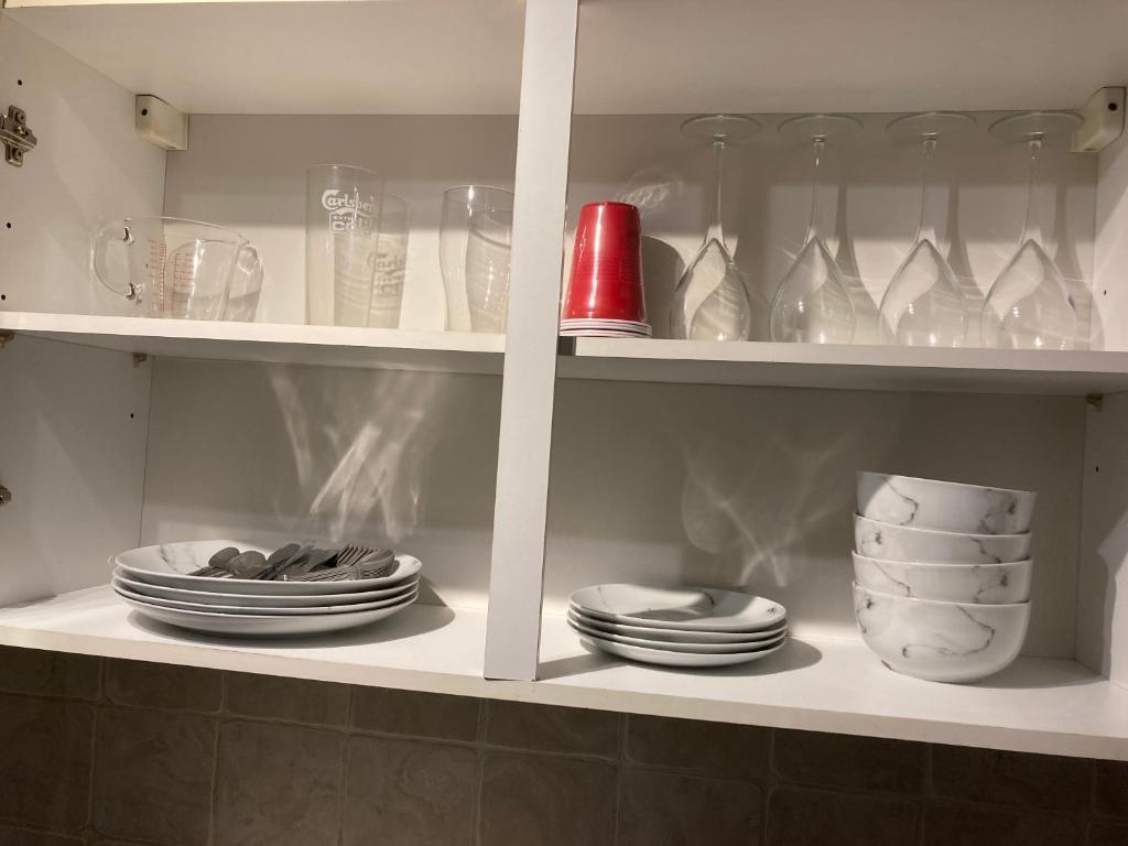 un armario blanco lleno de platos, tazones y vasos en Lovely 2 Bed House Apartment in Boston TownCentre, en Boston
