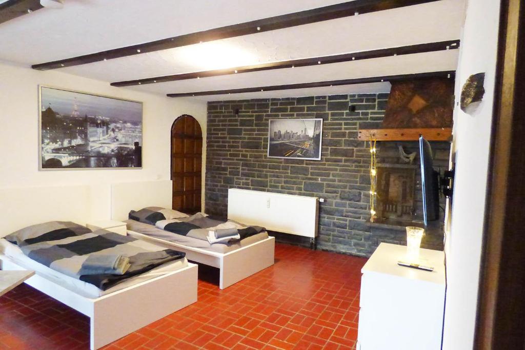 a room with two beds and a brick wall at Work&Stay Apartments Hellenthal in Hellenthal