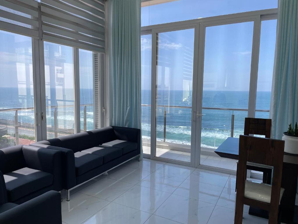 a living room with a couch and large glass windows at Lovely Sea View Apartment in Colombo