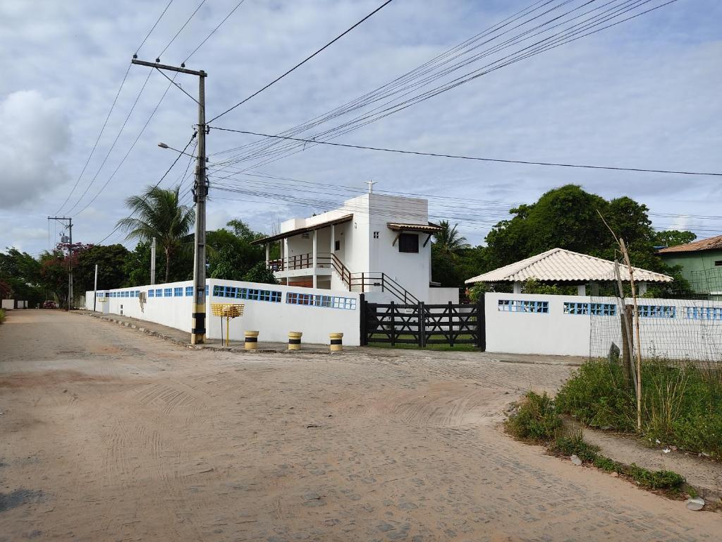 a white building with a fence next to a road at Chale do Guidon in Imbassai