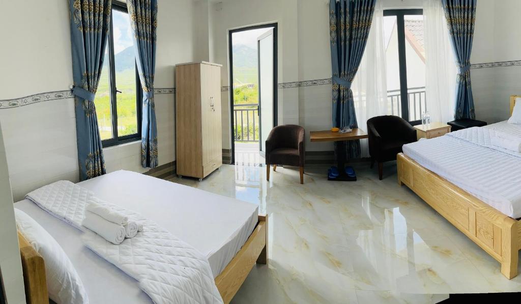 sypialnia z 2 łóżkami, biurkiem i oknami w obiekcie Hải Phong hotel w mieście Dien Khanh