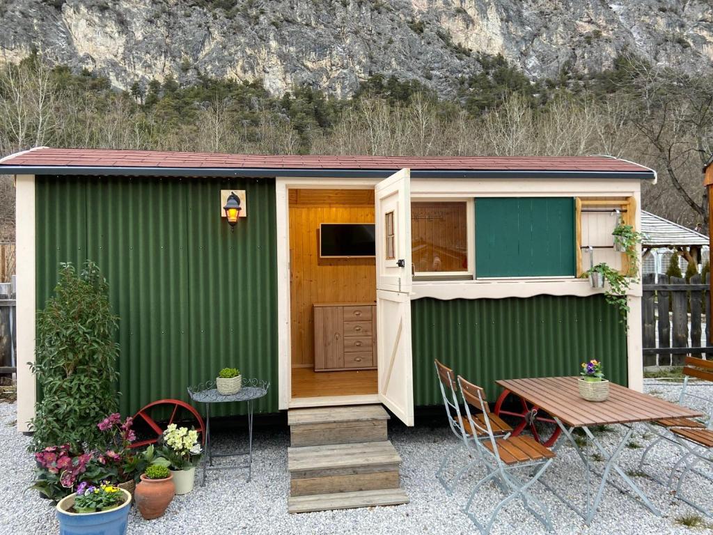 a green shed with a table and chairs and a table and a table at an der GEIERWAND in Haiming