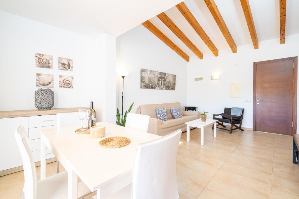a white dining room and living room with a table and chairs at Apartament Cala Anguila in Manacor
