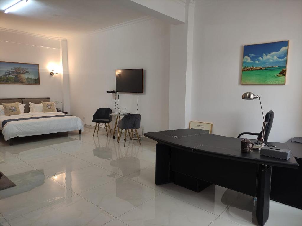 ein Hotelzimmer mit einem Schreibtisch, einem Bett und einem Schreibtisch in der Unterkunft Feima Hotel in Antananarivo