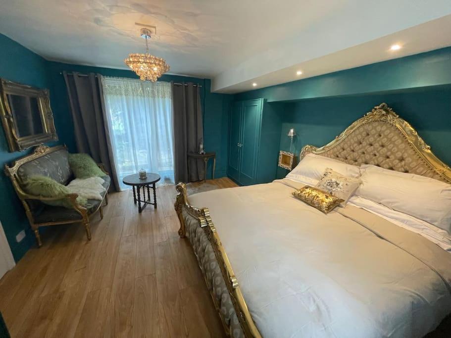 The Big Cosy Boudoir Bed + Hot tub في Harvington: غرفة نوم بسرير كبير بجدار ازرق