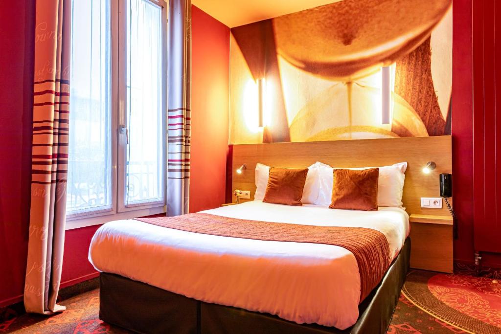 Pokój hotelowy z dużym łóżkiem z czerwonymi ścianami w obiekcie Hotel Ariane Montparnasse by Patrick Hayat w Paryżu