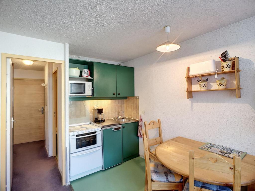 une petite cuisine avec des placards verts et une table en bois dans l'établissement Studio 4 pers, skis aux pieds, cuisine équipée - FR-1-178-321, aux Menuires