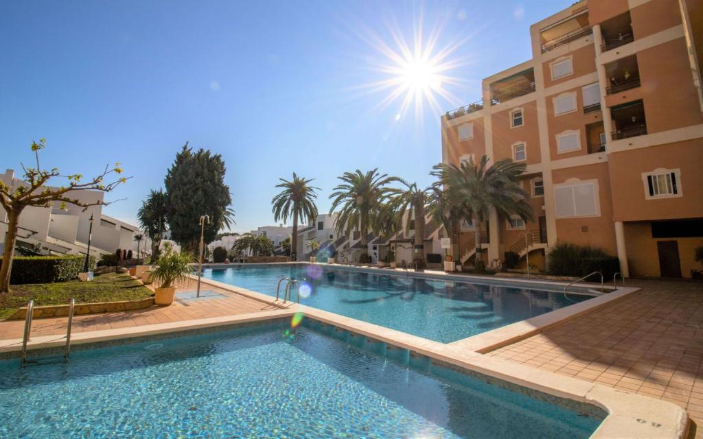 a large swimming pool with palm trees and buildings at Adosado con piscina a 50 metros de la playa - Las Fuentes ALBERT VILLAS in Alcossebre
