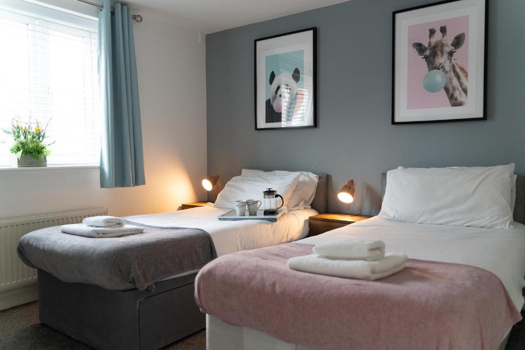 Dos camas en una habitación de hotel con toallas. en 3 Smart TVs, Sleeps 3, VAN PARKING, Fast WIFI en Corby