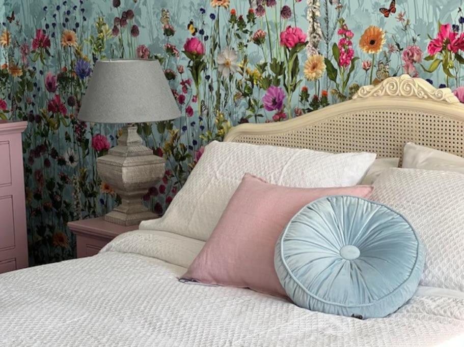 un letto con un cuscino e carta da parati floreale di Cosy country cottage in rural location a Moffat
