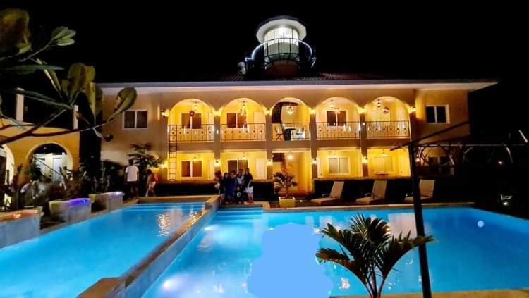 a hotel with a large swimming pool at night at Villa Del Faro in Batangas City