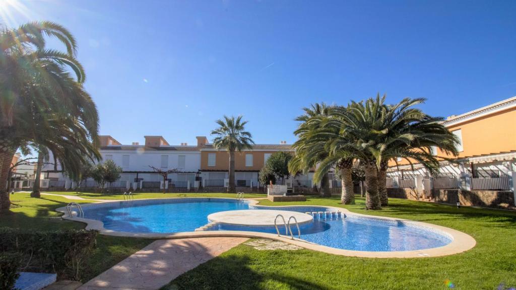 una piscina en un patio con palmeras en PALM BEACH 132 Adosado con jardin y piscina ALBERT VILLAS, en Alcossebre