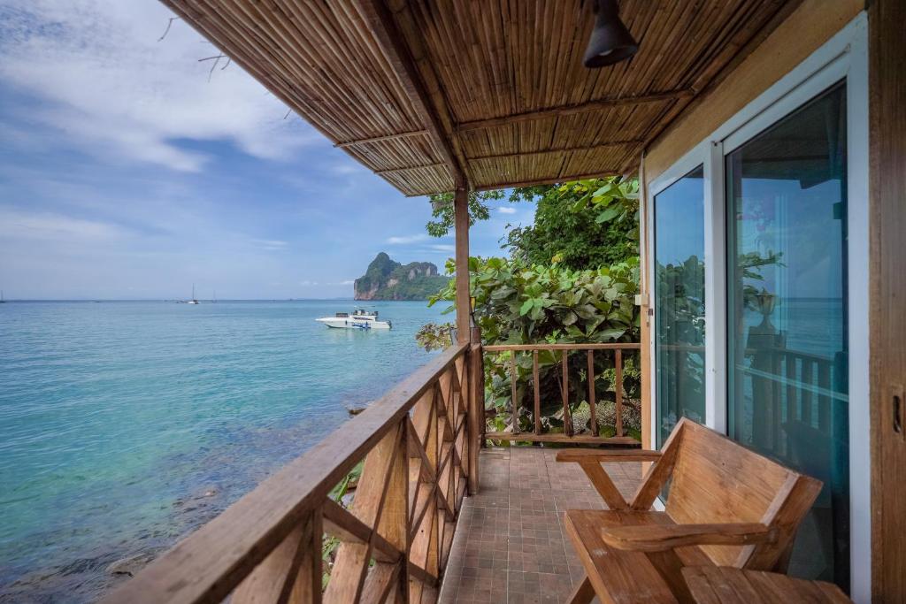 eine Veranda eines Hauses mit einer Bank und dem Meer in der Unterkunft Phi Phi Cozy Seafront Resort in Ko Phi Phi