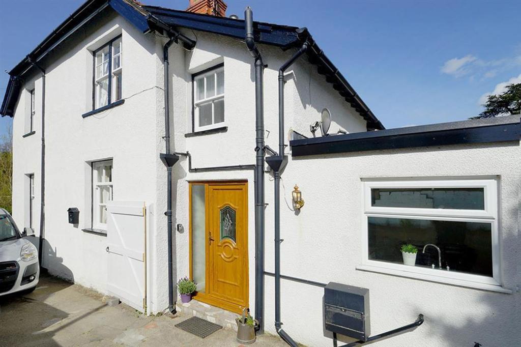 a white house with a yellow door and a car at Rhos Cottage in Conwy