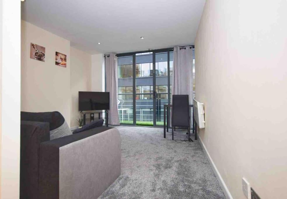 a living room with a couch and a large window at Superb Balconied 2Bedroom Flat in Heart of City Centre in Leeds