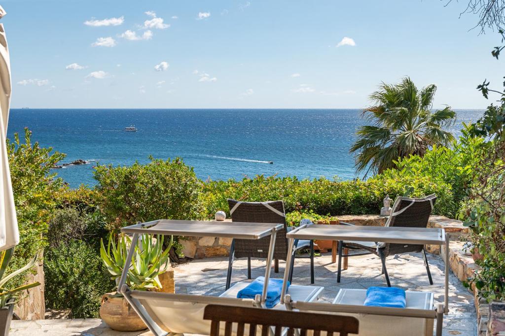una mesa y sillas con el océano en el fondo en Domus Luna Apartment with sea view Villasimius en Villasimius