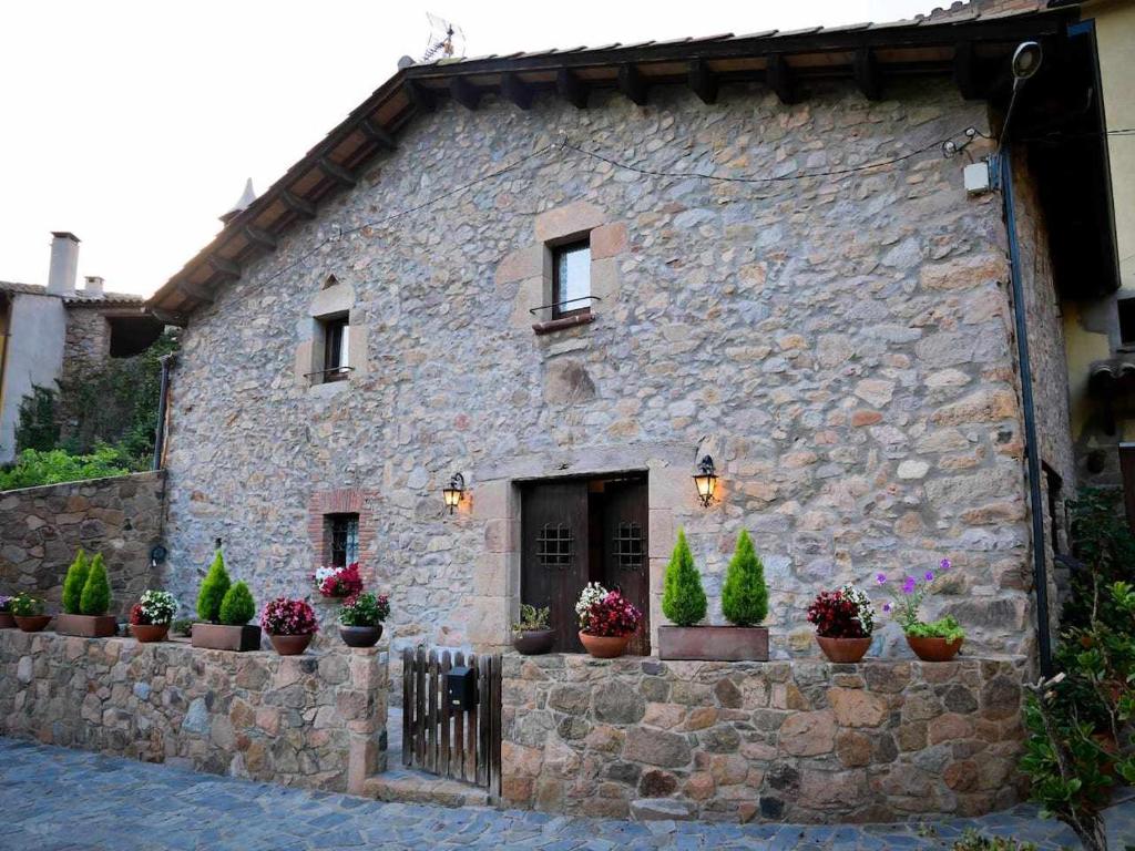 un bâtiment en pierre avec des plantes en pot devant lui dans l'établissement Can Toni Vell Espinelves, à Espinelvas