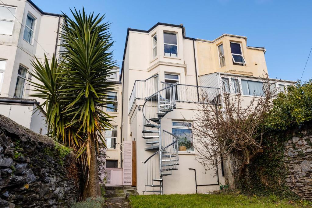 an apartment building with stairs in front of a palm tree at 5-Bed House with distant sea views in Plymouth in Plymouth