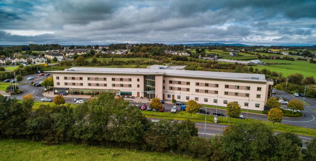 um grande edifício branco com uma estrada em frente em McWilliam Park Hotel em Claremorris