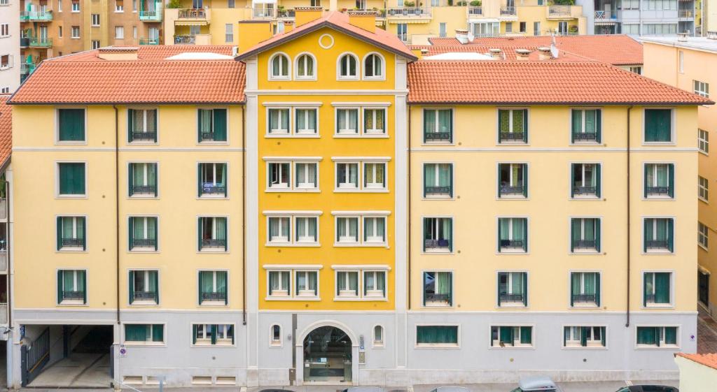un edificio alto de color amarillo con techo rojo en Residence Rialto, en Trieste