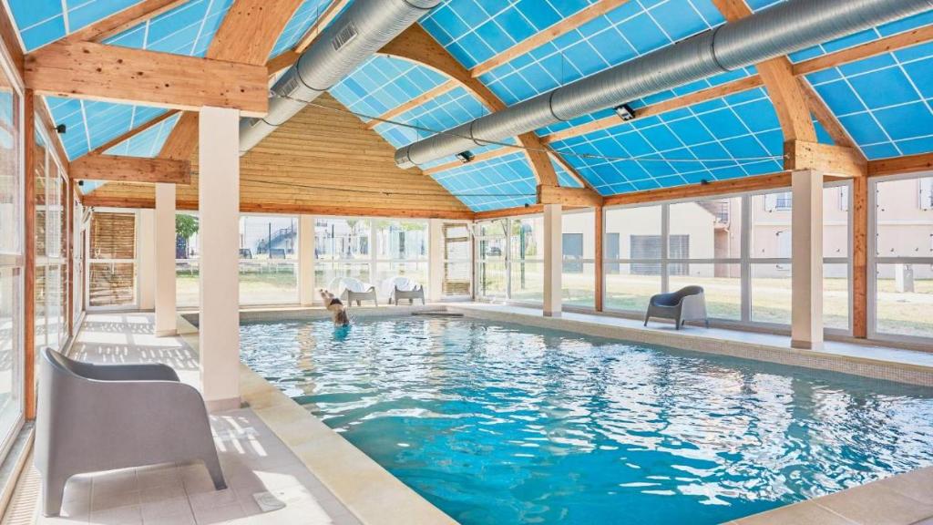 una piscina con techos azules y una gran piscina en Appart Hôtel 3* dans une résidence de tourisme, en Le Mée-sur-Seine