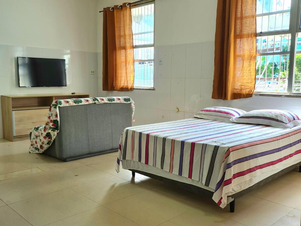 1 dormitorio con 1 cama, 1 silla y TV en Apt melhor localização da Barra, en Salvador