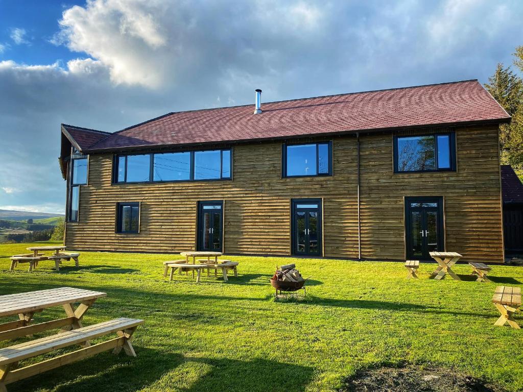 a large wooden house with picnic tables in front of it at The Lodge in Llanbrynmair