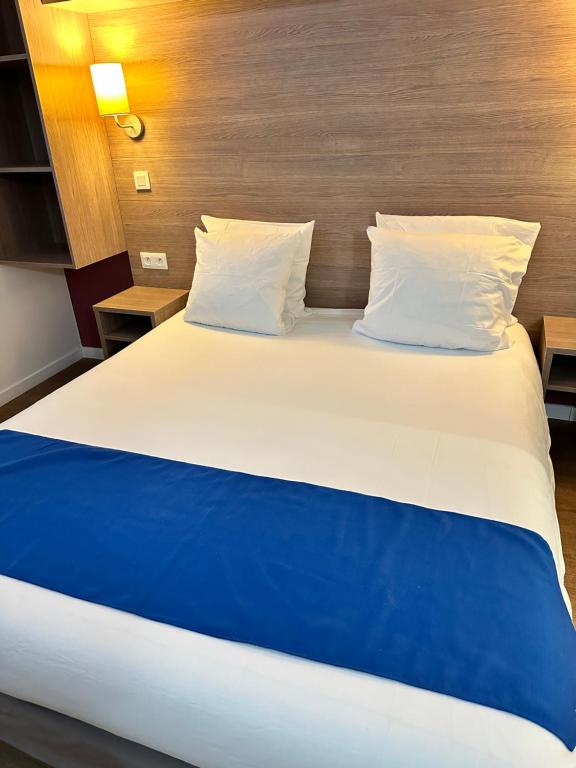Cama grande con sábanas y almohadas azules y blancas en Résidence Océane en Avrainville
