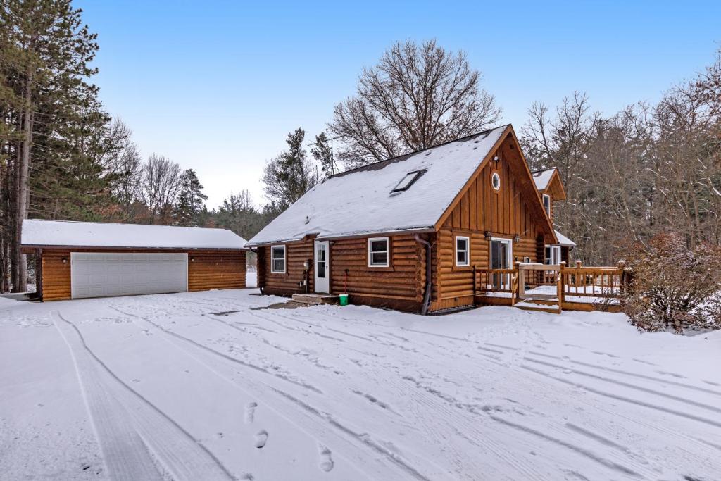 une cabane en rondins dans la neige avec une allée dans l'établissement The Logs, à Necedah