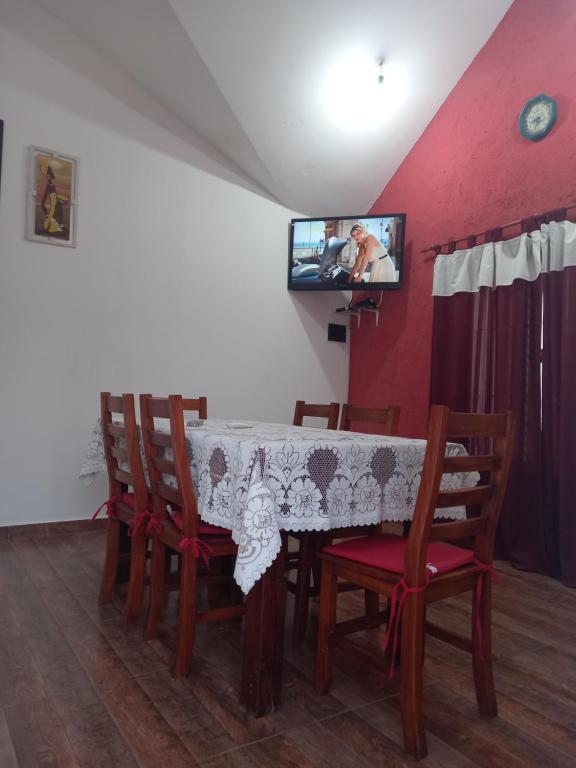 uma sala de jantar com uma mesa com cadeiras e uma televisão em El Piscui House em Merlo