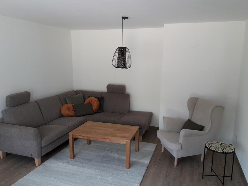 a living room with a couch and a table and a chair at Ferienwohnung Brehmbachgrund in Tauberbischofsheim