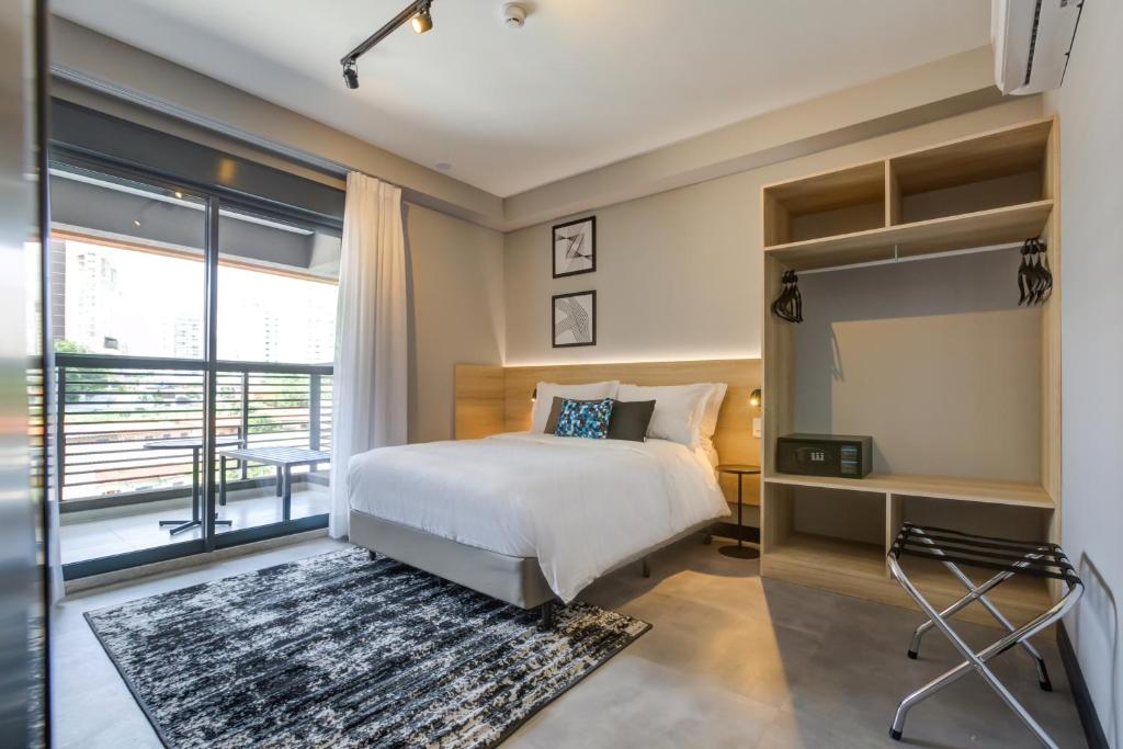 um quarto com uma cama e uma grande janela em Roomo Brooklin Morumbi Ejoy Residencial em São Paulo