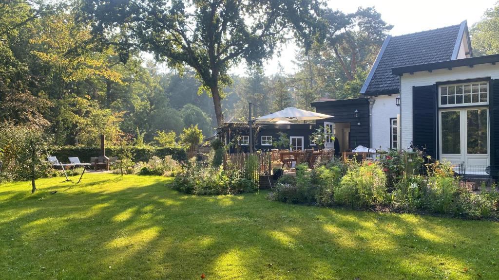 un patio con una casa con un jardín con césped sidx sidx sidx sidx en B&B Sur Place en Huizen