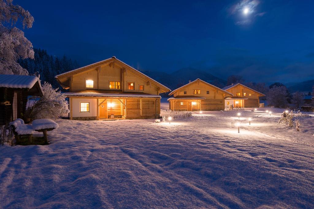 a cabin in the snow at night with lights at Lehenriedl Chalet in Wagrain