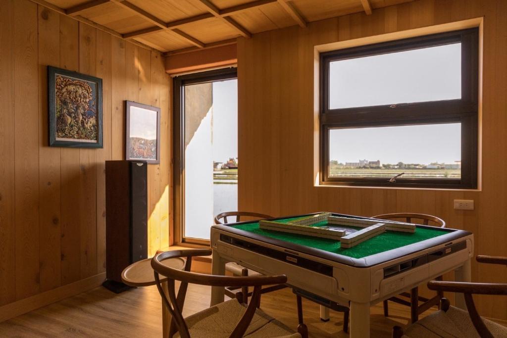 a ping pong table in a room with chairs and a window at 輕塵別院Serenegray B&amp;B in Wujie