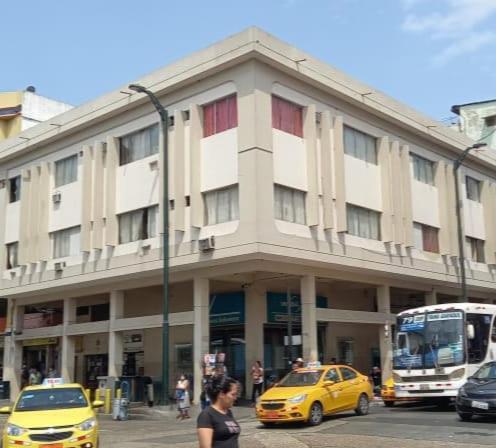 ein Gebäude auf einer Straße mit Autos und einem gelben Taxi in der Unterkunft HOTEL PRIMAVERA in Guayaquil