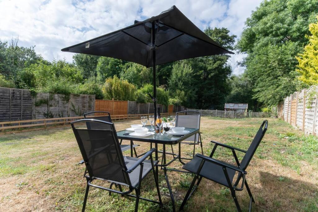 a table and chairs with an umbrella in a yard at Beautiful 2 Bedroom House With Spacious Garden BBQ in Brasted