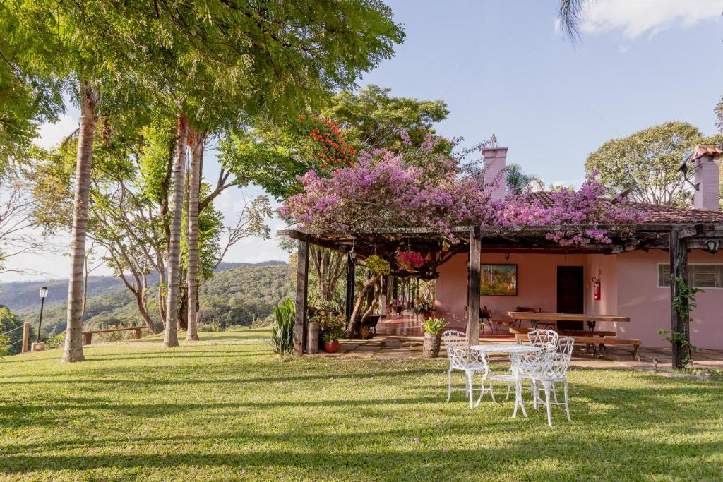 a house with a table and chairs in the grass at Pousada Rávis - Café e Descanso in Sabará