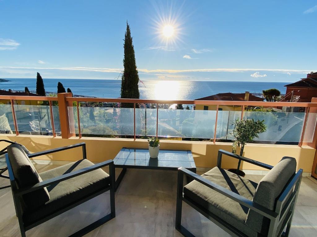 d'un balcon avec deux chaises et une table en verre. dans l'établissement Le Vigia-vue mer-terrasse-climatisation-parking, à Menton