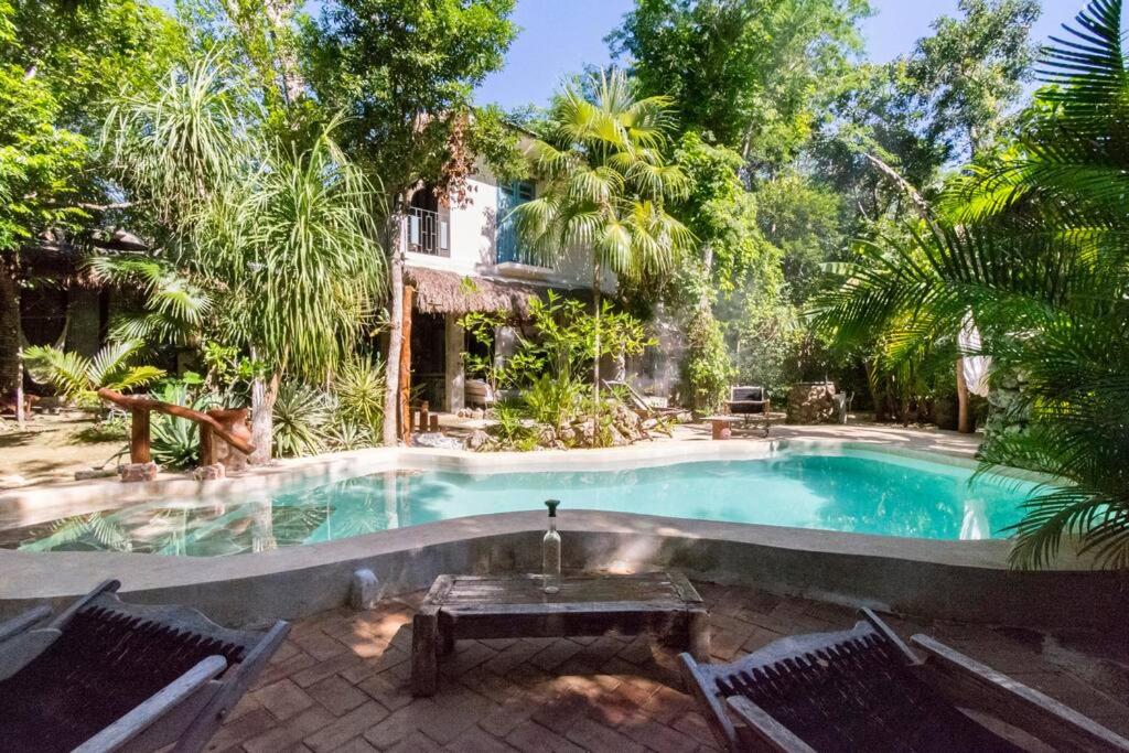 a swimming pool with a table and chairs in front of a house at VerdeAmar Eco Lodge Jungle Retreat in Chemuyil